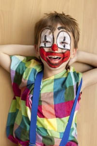 Smiling little boy masked as clown