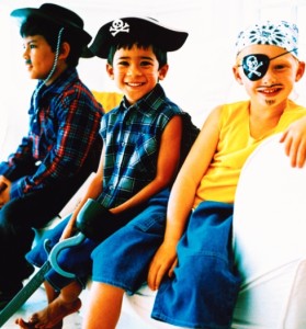 portrait of three young boys (5-8) sitting on a couch dressed as pirates and a cowboy
